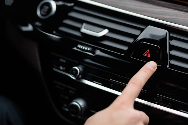 Man pressing red triangle car hazard light button — Stock Photo, Image