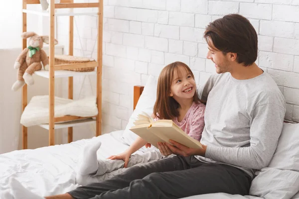 Far och lycklig dotter läser bok i sovrum — Stockfoto