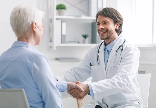 General practitioner shaking hands with healthy patient