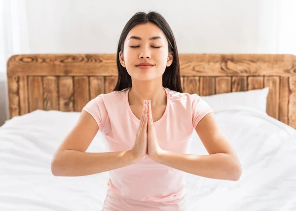 Pacífica ásia mulher orando ou meditando sentado no cama interior — Fotografia de Stock