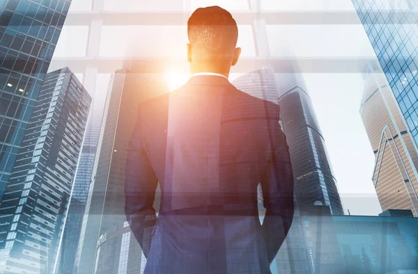 Business and urban life. Double exposure of businessman looking at city with skyscrapers at sunrise, collage