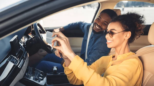 アフリカ系アメリカ人のカップルが新しい車の中でセルフィーを作る,パノラマ — ストック写真