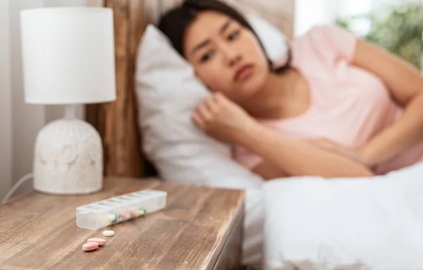 Ásia menina tomando dormir pílulas ter insônia deitado no cama — Fotografia de Stock