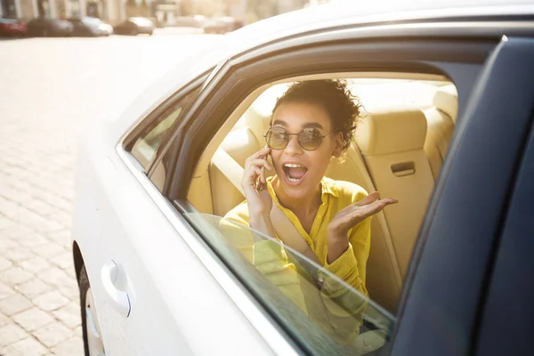 車の中で座っている携帯電話で話す楽しいアフリカの女性 — ストック写真