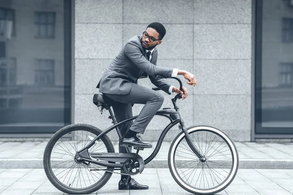 Bonito empresário afro andando de bicicleta para o trabalho — Fotografia de Stock