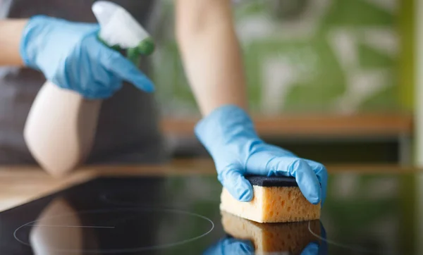 Femme méconnaissable polissant le plan de travail de la cuisine avec un détergent pulvérisateur — Photo