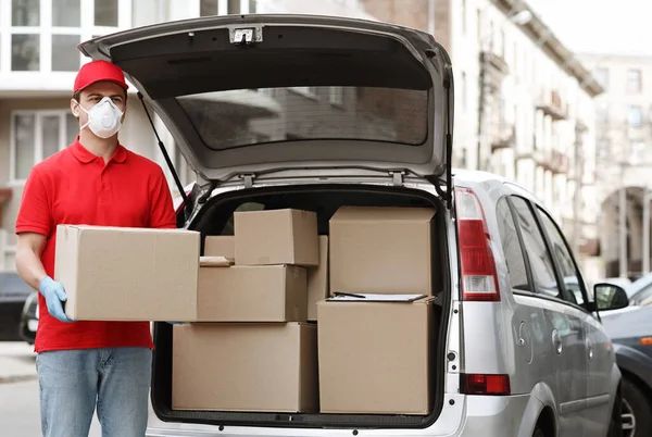 Muitas encomendas, um monte de entregas conceito. Courier detém grande parcela perto do carro — Fotografia de Stock