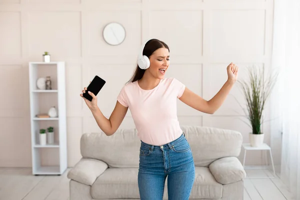 Mujer con Smartphone y auriculares escuchando música en casa — Foto de Stock