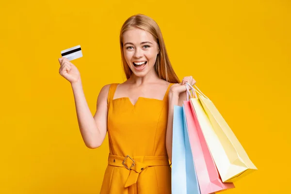 Försäljning och rabatter. Spännande flicka innehav shoppingväskor och kreditkort — Stockfoto