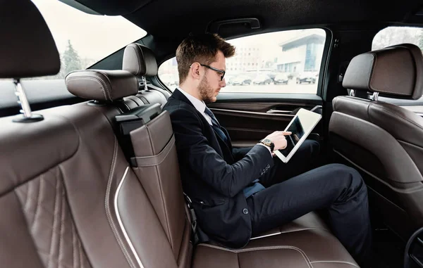 Pengusaha muda menggunakan laptopnya di mobil mewah — Stok Foto