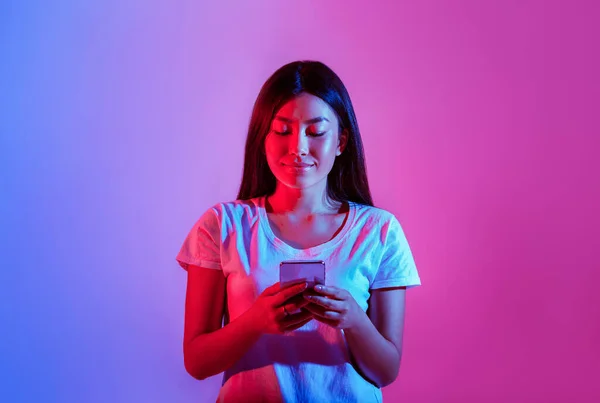 Les réseaux sociaux. Asiatique fille regarde smartphone et types — Photo