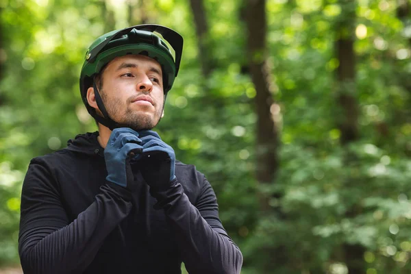 Kolarz w kasku sportowym na tle lasu — Zdjęcie stockowe