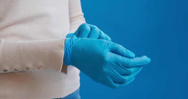 Женщина снимает голубые медицинские резиновые перчатки — стоковое видео