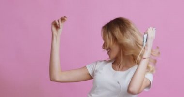 Kulaklıklı sarışın kız müzik dinliyor ve dans ediyor.