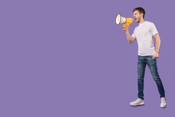 Agresszív ember kiabál hangosbeszélővel, elszigetelve a lilától — Stock Fotó