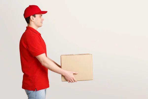 Trabajo de mensajero. Deliveryman en uniforme sostiene la caja de cartón — Foto de Stock