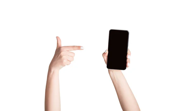 Girl pointing at mobile phone with empty screen, isolated on white. Mockup for your website or app design — Stock Photo, Image