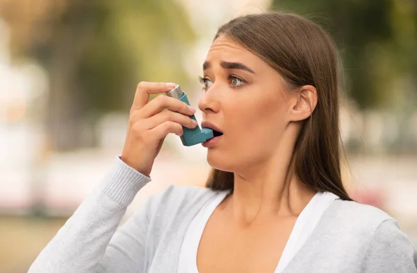 Mulher com ataque asmático usando inalador em pé ao ar livre — Fotografia de Stock