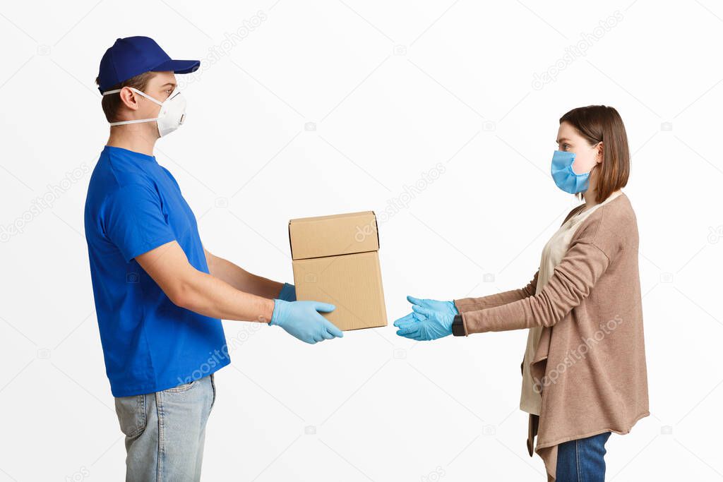 Courier in protective gloves and mask hands over package to client