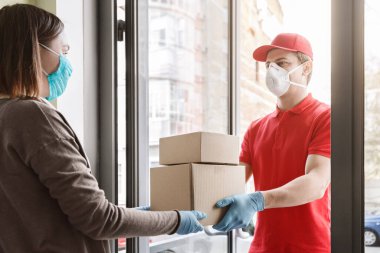 Coronavirus konsepti sırasında müşterinin korunması. Teslimatçı evdeki müşteriye kutu verir.