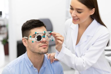Optometrist hasta vizyonunu deneme çerçevesi ile kontrol ediyor