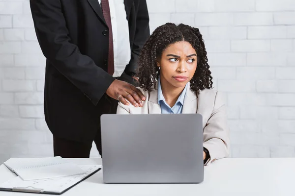 Mau comportamento sexual no local de trabalho. Africano chefe americano tocando seu ombro subordinados do sexo feminino no escritório — Fotografia de Stock