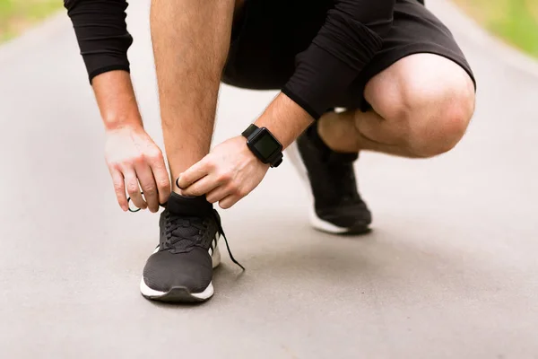 Nahaufnahme eines jungen Mannes beim Binden von Sportschuhen — Stockfoto