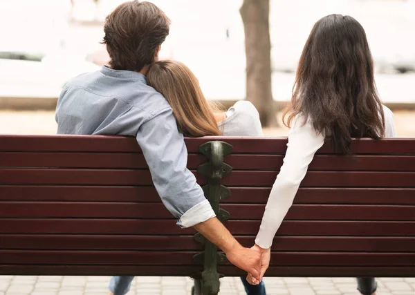 Novio sosteniendo las manos con novias amigo sentado en el banco al aire libre — Foto de Stock