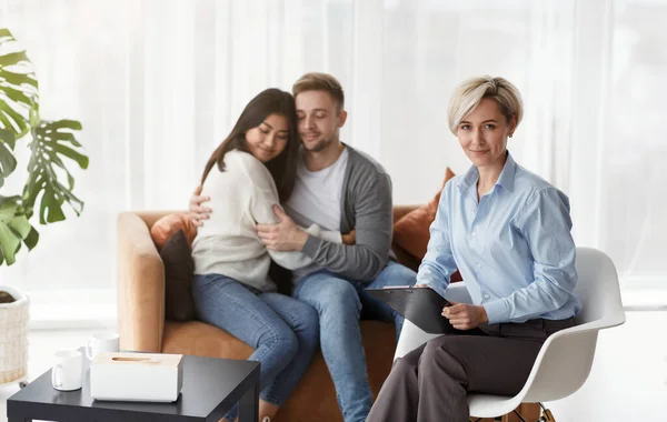 专业的家庭心理学家坐在治疗后的夫妻身边 — 图库照片