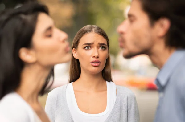 Девушка смотрит на своего изменяющего бойфренда целующегося с другой женщиной на улице — стоковое фото