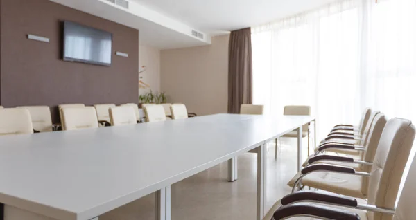 Salle de réunion avec grande table blanche, chaises — Photo