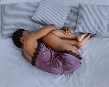Acı ve depresyon. Kız kıvrılıp yatıyor, aybaşı ve kritik günlerden muzdarip.
