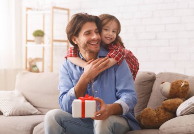Neşeli anaokulu kızı babasına arkadan sarılıyor.