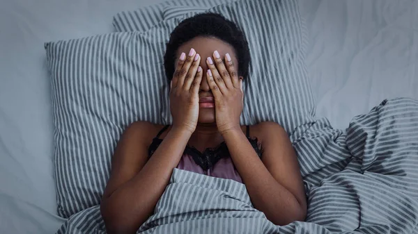 Afroamericano ragazza chiuso gli occhi con le mani a letto — Foto Stock