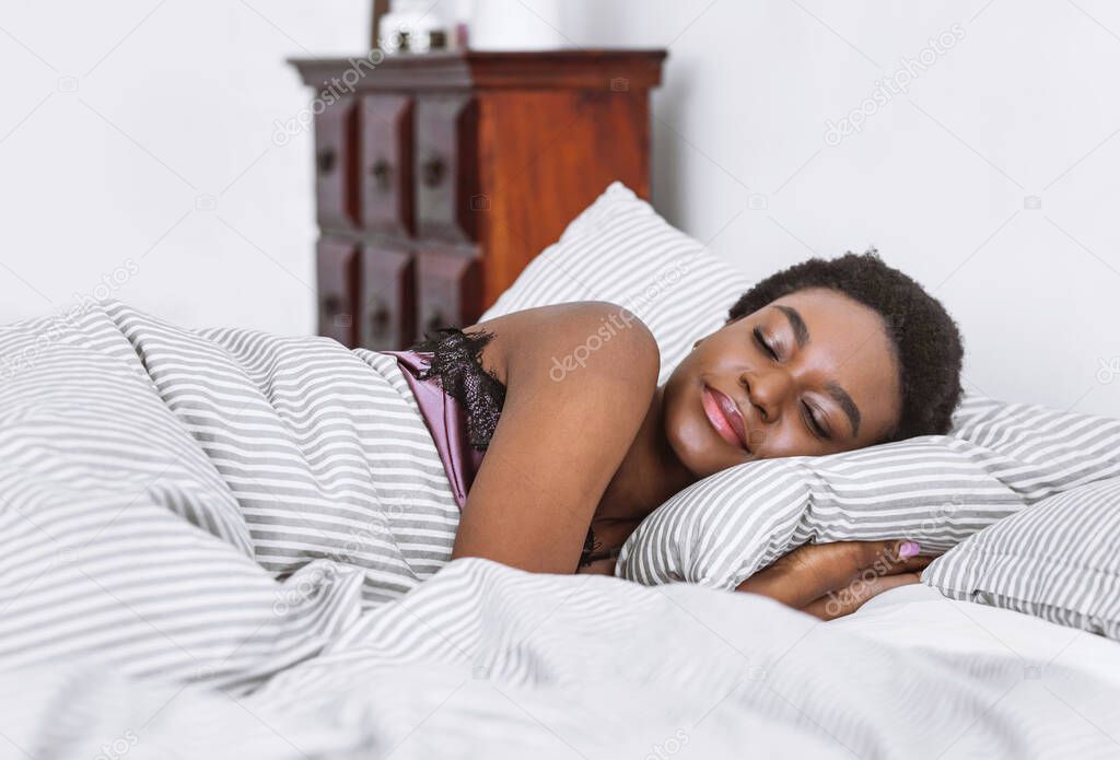 African american girl sleeps in bed in bedroom interior