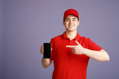 Gülümseyen kurye boş ekran ile akıllı telefonu işaret ediyor