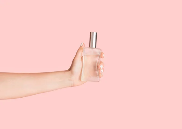 Meisje met fles van natuurlijke parfum op roze achtergrond, close-up — Stockfoto