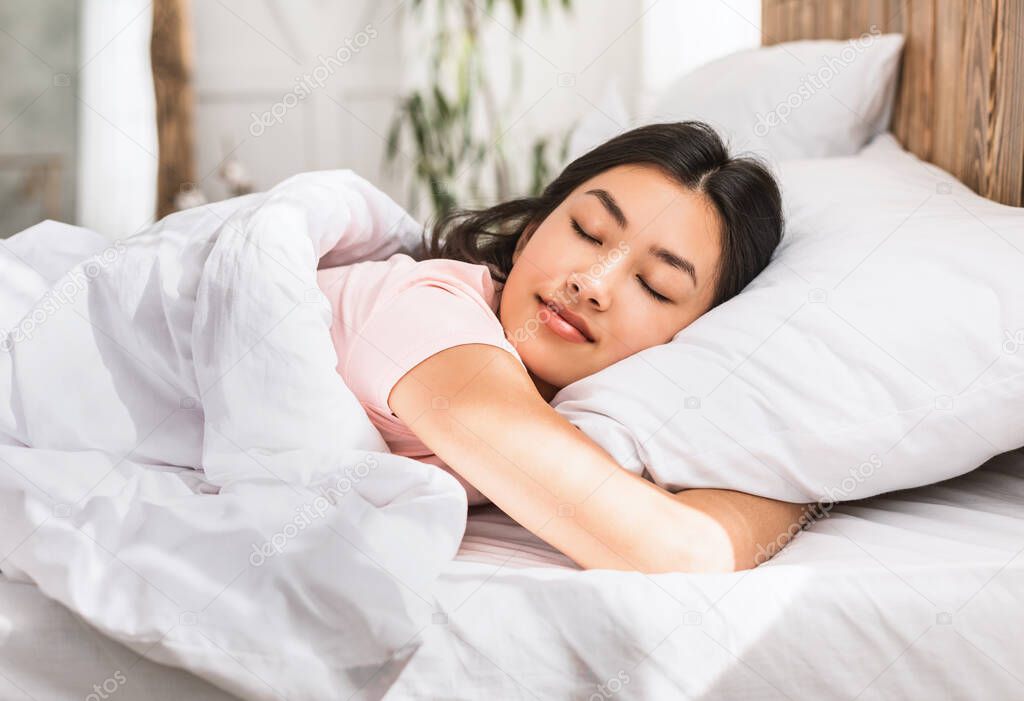 Asian Girl Sleeping Hugging Pillow Resting In Comfortable Bed Indoors