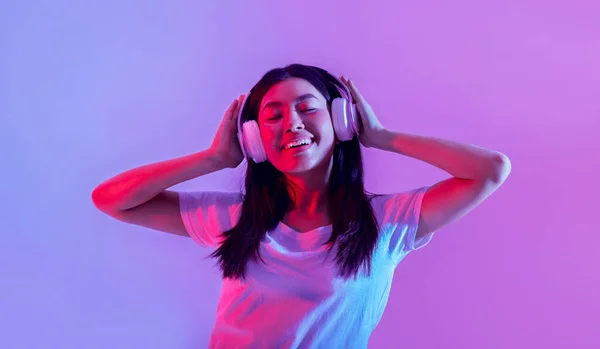 大きなヘッドフォンで幸せなアジアの女の子は歌から喜びの感情を表現します — ストック写真