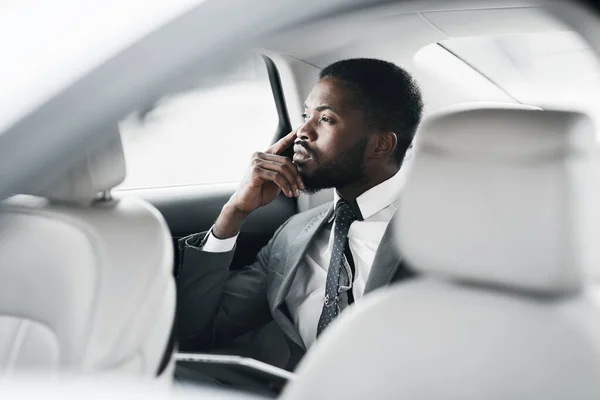 Ragionevole uomo d'affari nero seduto in auto guardando fuori dalla finestra — Foto Stock