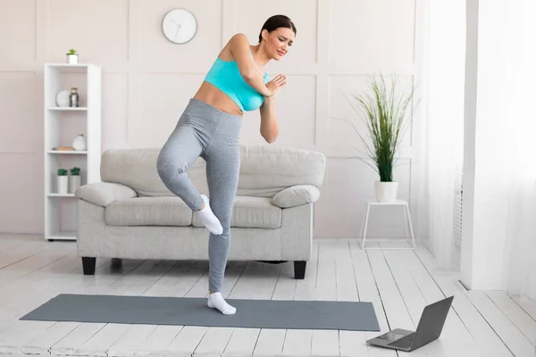 Жінка починає практикувати йогу онлайн вправи на ноутбуці вдома — стокове фото