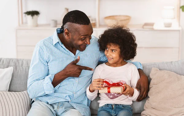 Szülinapi ünnepség otthon. Afrikai-amerikai gyermek és nagyapja ünnepi ajándékokat cserélnek a nappaliban — Stock Fotó