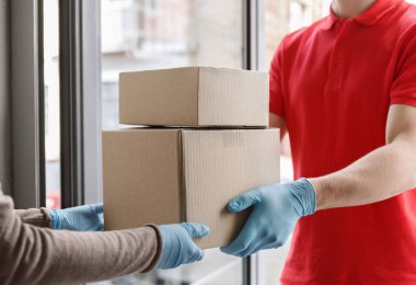 Coronavirus konsepti sırasında modern teslimat. Teslimatçı müşteriye kutu verir.