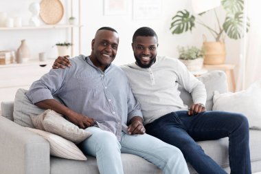 Yetişkin oğluyla evde poz veren kıdemli Afrikalı adamın portresi.