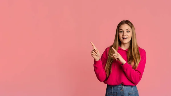 Menina adolescente com a boca aberta aponta com os dedos para um espaço vazio — Fotografia de Stock