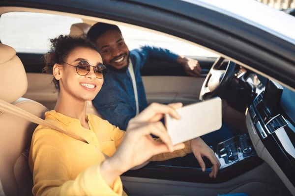 Alegre cónyuges haciendo selfie sentado en coche viajando en vacaciones —  Fotos de Stock