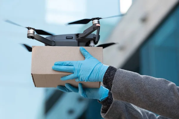 Drone quadricottero consegna di un pacco e le mani che ricevono il pacco — Foto Stock