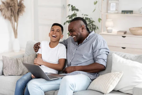 Preteen negro chico viendo comedia película en el ordenador portátil con el abuelo y riendo — Foto de Stock
