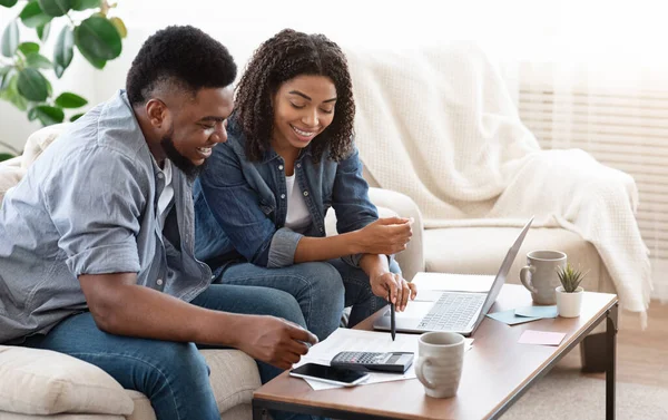Lächelndes schwarzes Paar diskutiert Gesamtbetrag ihrer Ausgaben zu Hause — Stockfoto