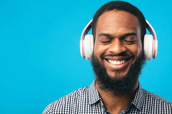 Sonriente afro chico disfrutando de la música usando sus auriculares —  Fotos de Stock